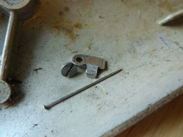 Found inside the lower cover: A small bracket with screw, one pin, and parts of broken needles.
